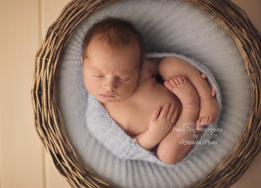 billede af nyfødt dreng sovende i kurv med blåt tæppe på ryggen