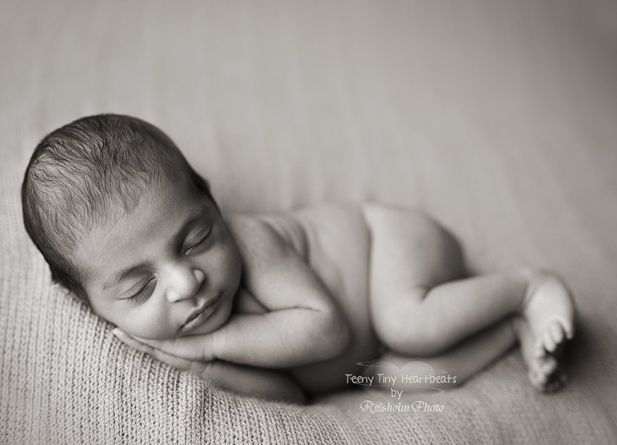 foto af nyfødt baby sovende på siden med hænderne under den ene kind i sort hvid