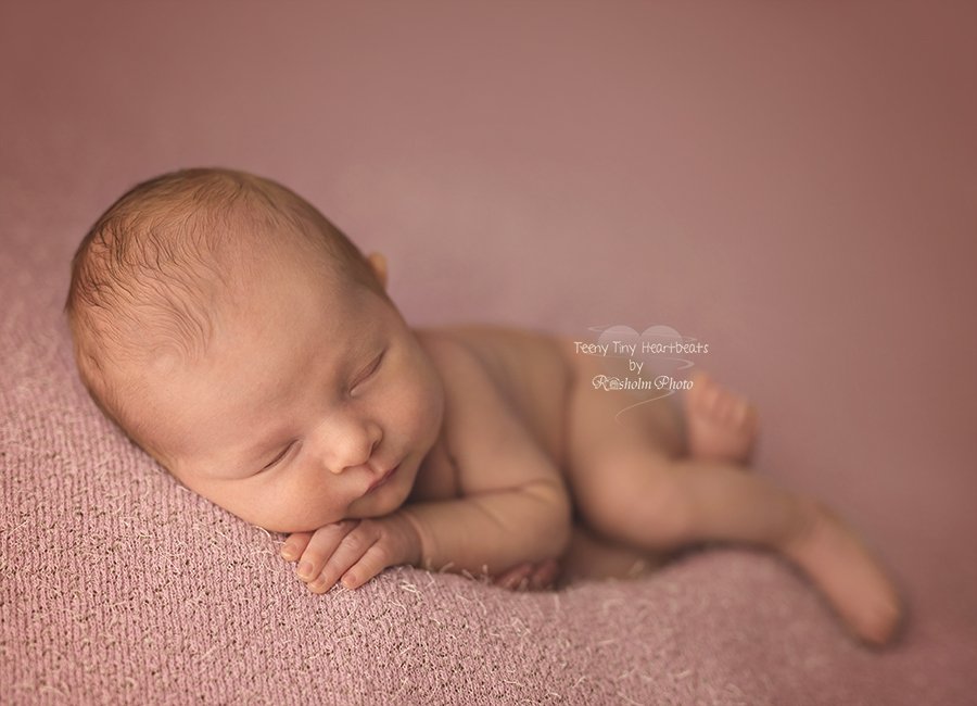foto af newborn pige liggende på lyserødt tæppe - sovende