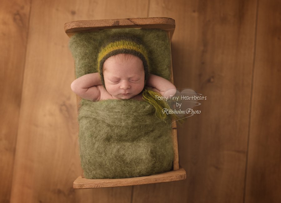 billeder af newborn dreng sovende i seng med grøn tæppe og hue med træbaggrund