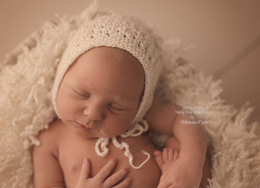 billede af nyfødt pige med hue i creme farve i kasse