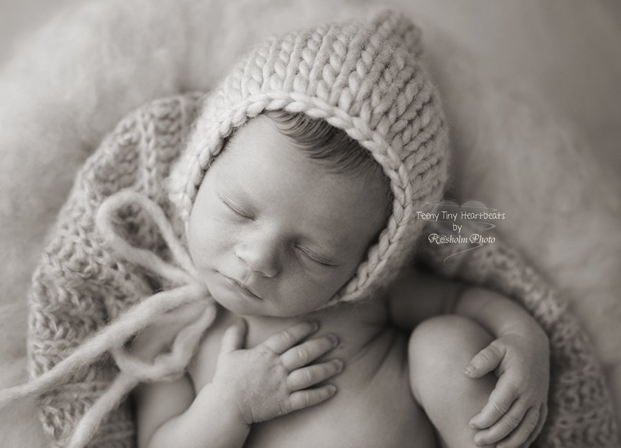 billede i sort hvid af nyfødt dreng fotograferet oppe fra med hue
