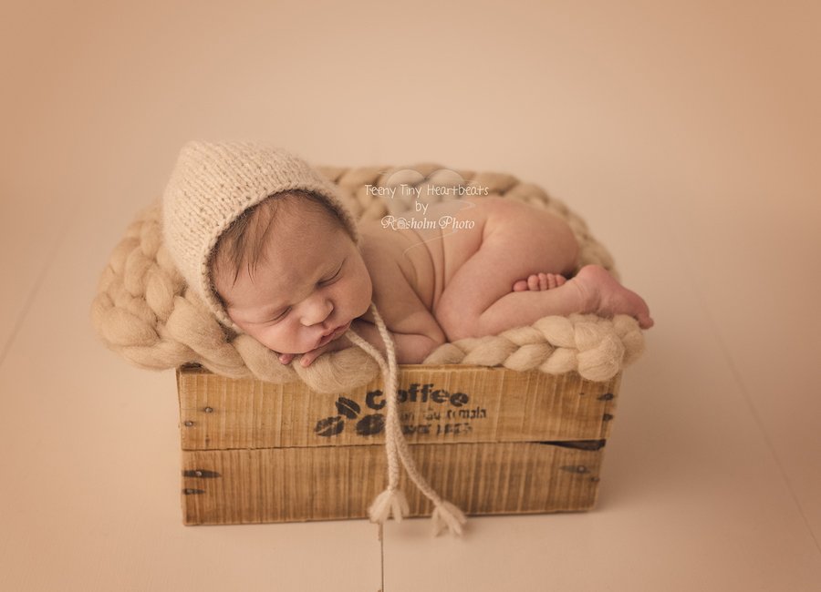 nyfødt foto af dreng sovende med creme tæppe og hue i træ kasse hos fotograf Teeny Tiny Heartbeats