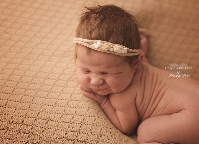 nyfødt pige med grimasse sovende på maven hos fotograf i silkeborg