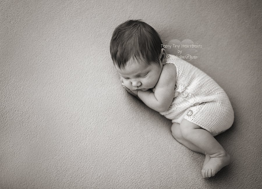 nyfødt foto af pige sovende på siden på tæppe i sort hvid