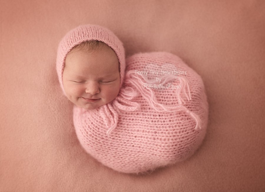 nyfødt sovende pige pakket ind i lyserød pose