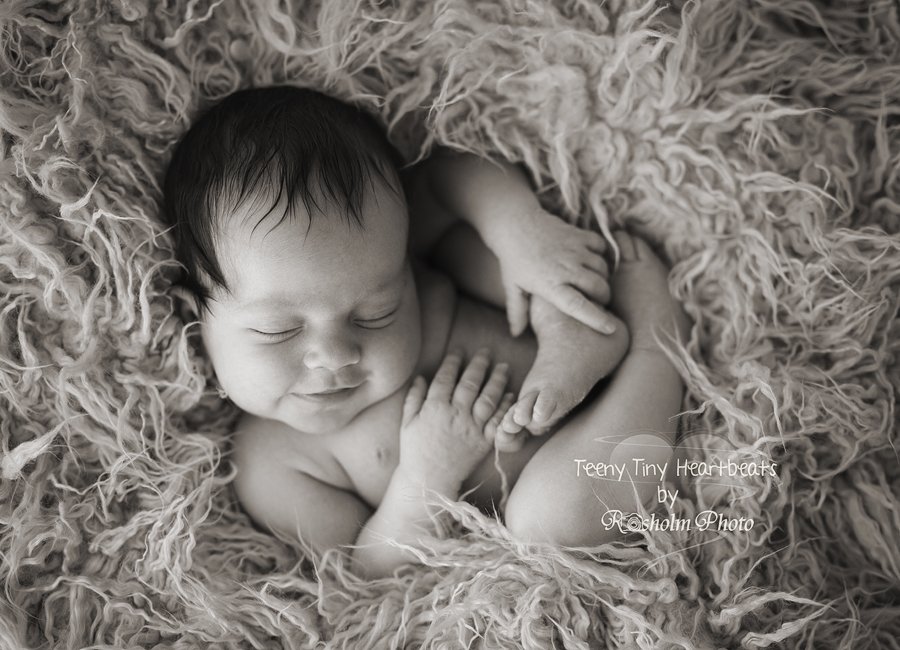 nyfødt pige sovende nede i tæppe på ryggen i sort hvid