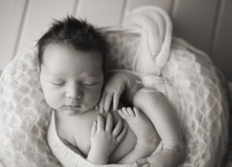 sort hvid billede af nyfødt sovende i lys kurv