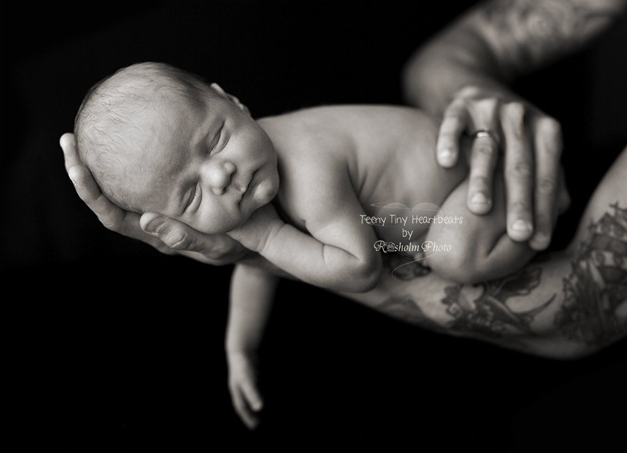 sort hvid foto af nyfødt på fars strakte arm i sort hvid